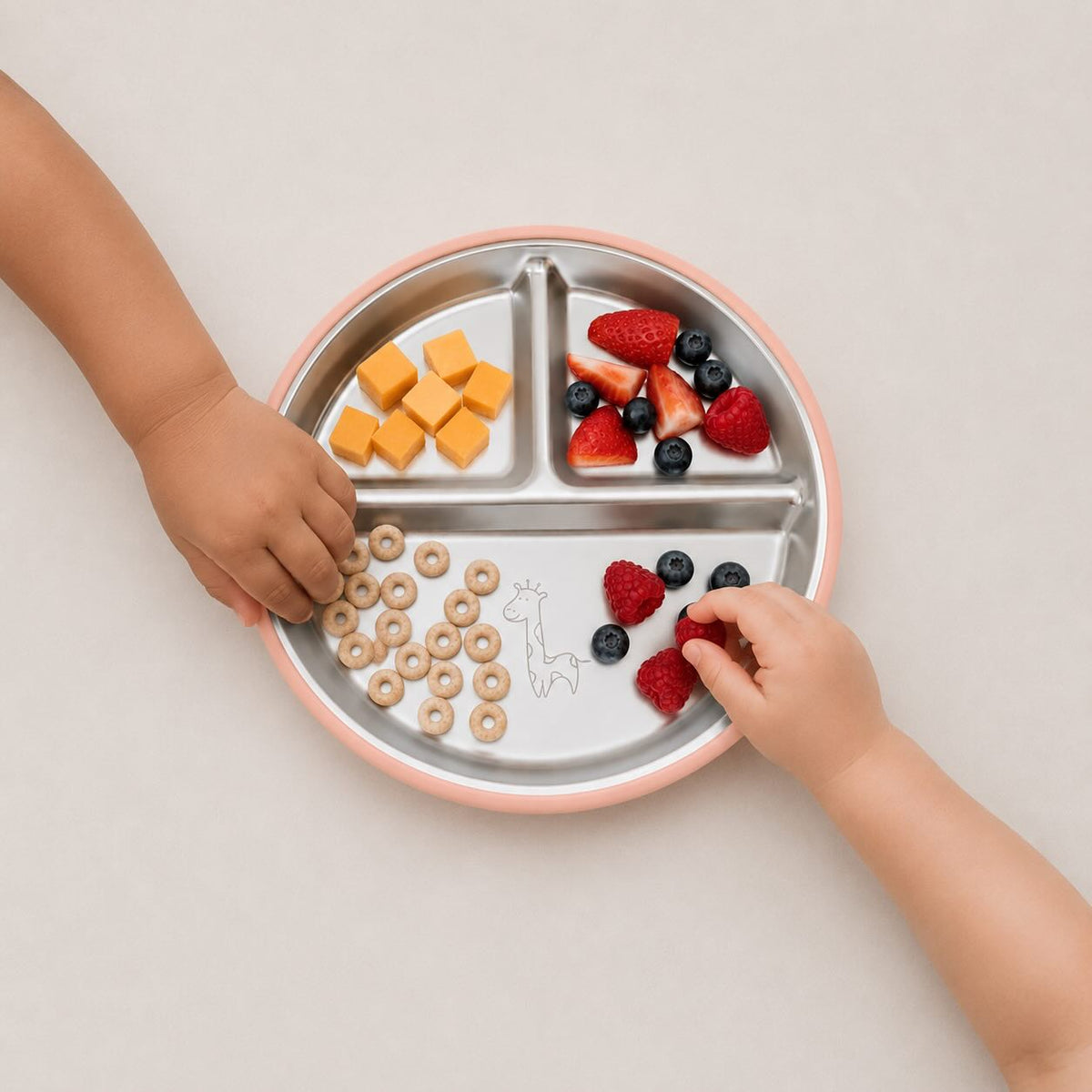 Toddlers eating snacks from a BRAI + CO. baby and toddler stainless steel and silicone divided plate